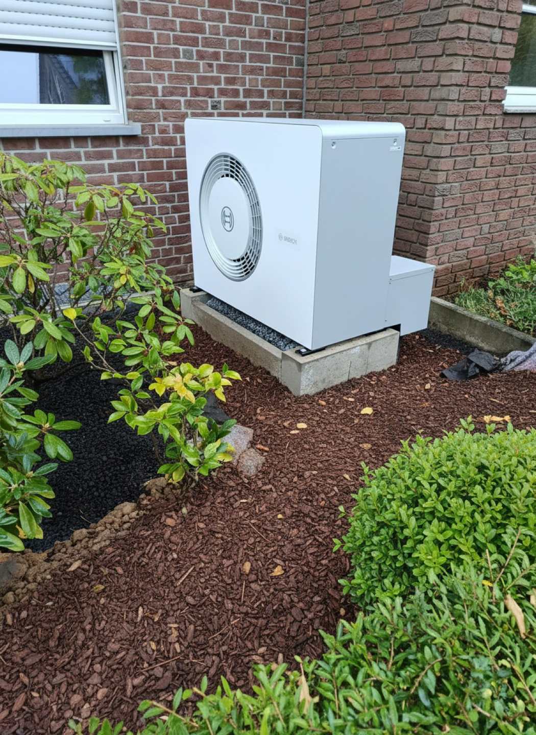 Wärmepumpen-Außeneinheit im Gartenbeet